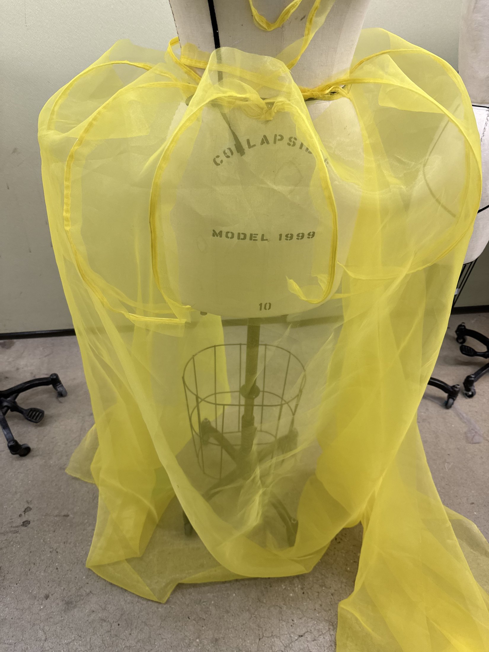 Sheer yellow fabric draped over a dress form